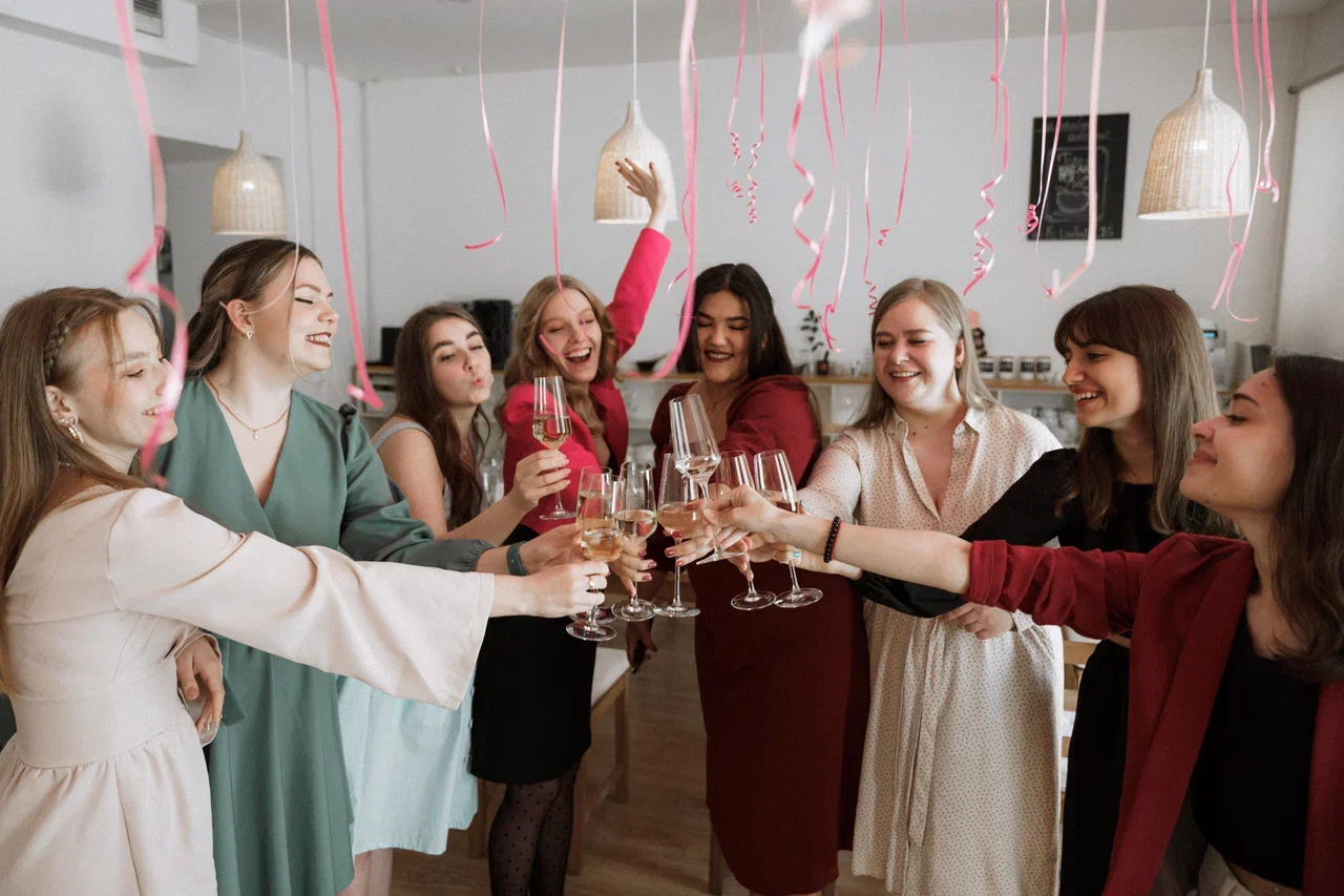 Девушки чекаются бокалами во время кулинарного девичника в СПб